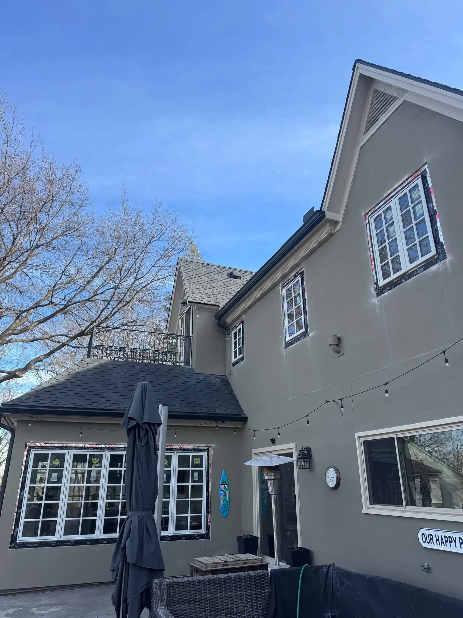 Two-story home with new charcoal gray asphalt shingle roof, gray siding, white-trimmed windows, and updated fascia