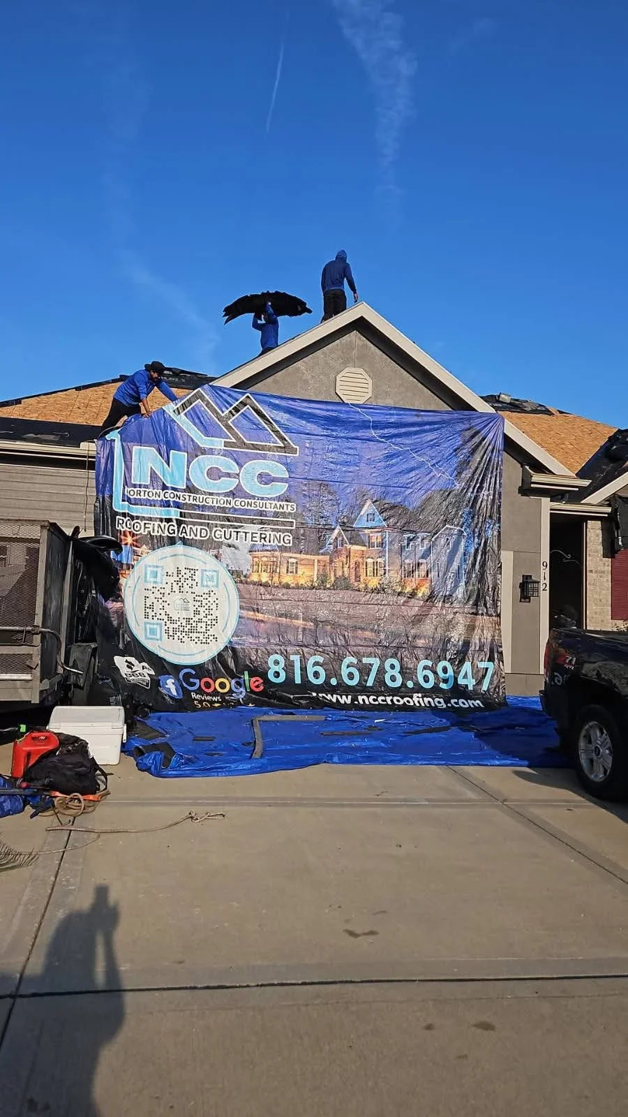 Residential roof covered with blue protective tarp during roofing work, asphalt shingles visible